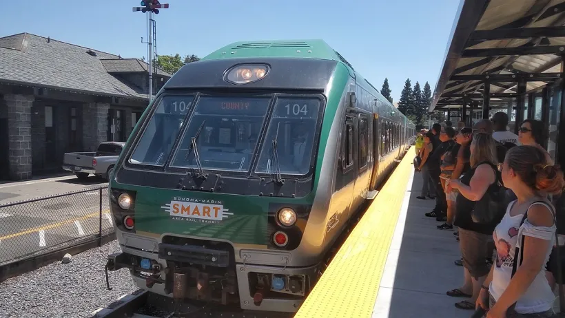 Green SMART train at platform full of people in Santa Rosa, California.