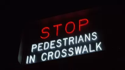 "Stop - Pedestrians in crosswalk" sign in white and red lights.