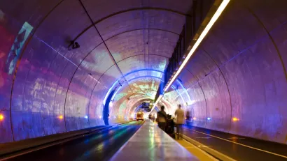 Tunnel for pedestrians, bikes, and buses in Lyon, France lit up with purple lights.
