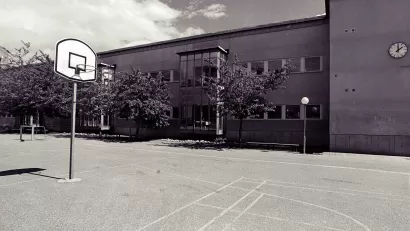 Low-saturation image of a concrete schoolyard with basketball hoop