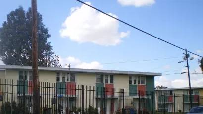 Two-story apartment building behind black iron fence in Pacoima, California