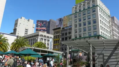 People sitting at outdoor tables with green umbrellas in Union Square, San Francisco.