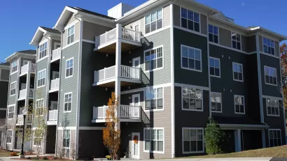 Four-story gray apartment building in suburban area