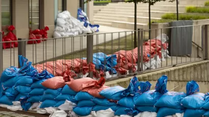 Red, white, and blue sandbags stacked along bridge railing and building doors and windows.