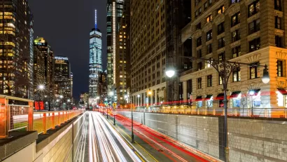Blurred traffic at night passing through Battery Park Tunnel into New York City with One World Trade Center in background.