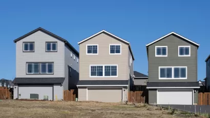 Three new single-family homes in a row on a lot with no trees.