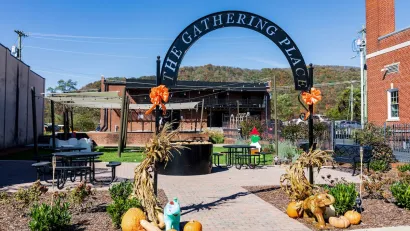 Public space with seating and 'The Gathering Place' metal sign on gateway arch in Erwin, TN.