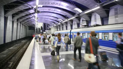 Busy subway station with people walking on platform and train stopped.