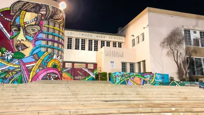 Colorful murals on exterior of Hollywood High School in Los Angeles, California against night sky.