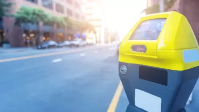 Close-up of yellow and grey smart parking meter with blurred city street in background.