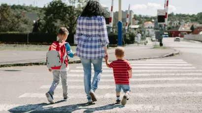Woman walking two small children across crosswalk.