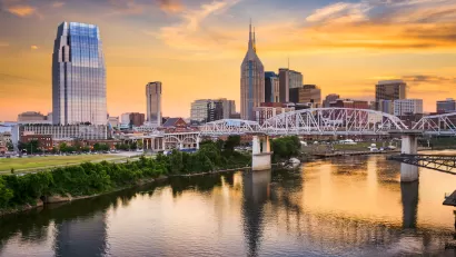 Sunset view of downtown Nashville, Tennessee skyline from across a river.