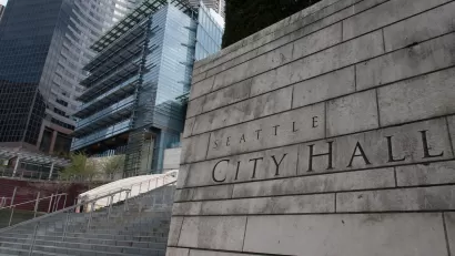 Close-up of carved Seattle City Hall title on front of concrete buildin next to staircase.