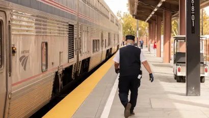 Conductor walks down platform next to Amtrak train at station in San Jose, California.