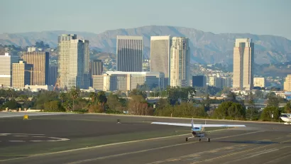 Small plane on runway at Santa Monica airport with high-rise buildings in background.