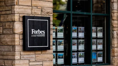 Real estate listings in window of Forbes Properties office.