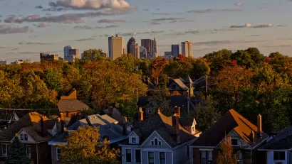View of homes nestled among green trees with Columbus, Ohio skyline in background