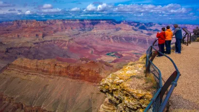 Two children and an adult looking out over railing at Grand Canyon.
