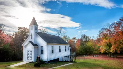 Small white wooden church in rural setting.