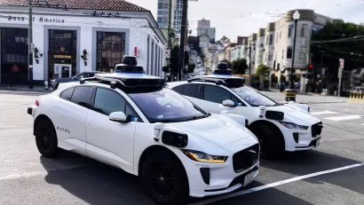 Two white Waymo robotaxis parked on street in San Francisco, California.