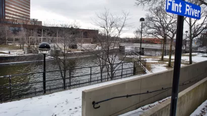 Flint River with blue sign on post in winter.