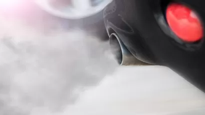 Close-up of car tailpipe with smoke coming out.