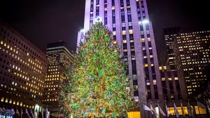 View of Rockefeller Center Christmas tree lit up at night in front of 30 Rock high-rise.