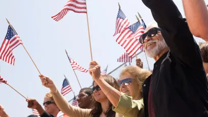 Group of senior citizens waving small American flags.