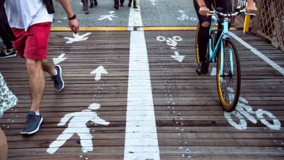 Close-up on wooden section of bike and pedestrian path marked with ped symbols on one side and bike symbols on the other.