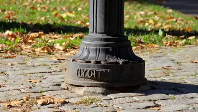 CLose-up of bottom of lamp post with NY CITY plaque on cobblestone sidewalk in Central Park, New York City.