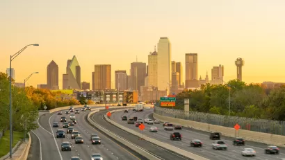 View of Dallas city skyline with moderately busy freeway in foreground at twilight.