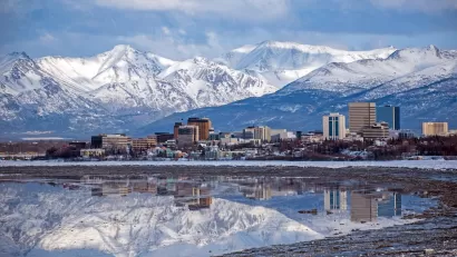 Anchorage, Alaska skyline with snowy mountains in background.