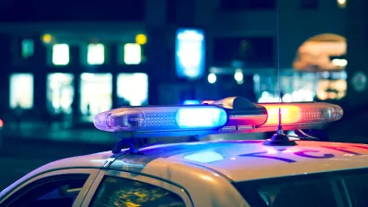 Nighttime view of blue and red lights on top of a white police car.