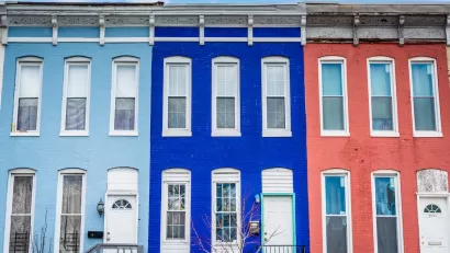 Brightly colored pale blue, dark blue, and coral row houses in Baltimore, Maryland.