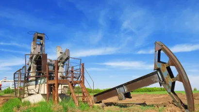 Defunct oil well disassembled in green field.