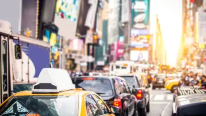 Blurred view of NEw York City traffic near Times Square with yellow cabs and black cars.
