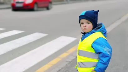 Child wearing yellow reflective safety vest looking before crossing street.