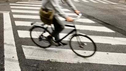 Person on bike riding across zebra crosswalk in city.