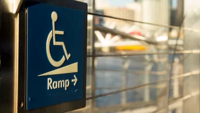 Close-up of blue and white wheelchair ramp sign with arrow pointing right.