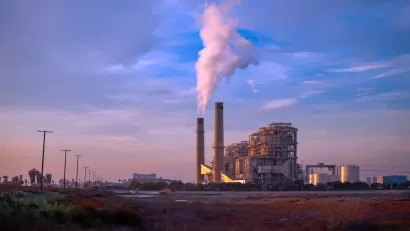 Natural gas power plant with two tall smokestacks against blue and purple sunset sky
