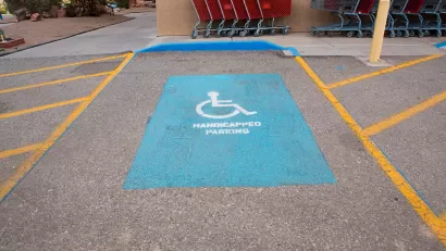 A handicap parking space with yellow painted wheelchair symbol and yellow hatched space on both sides.
