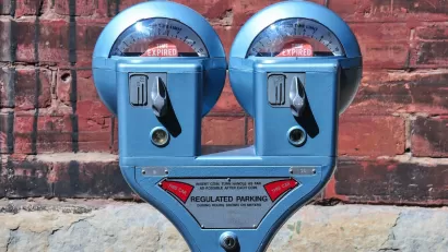Close-up of old-fashioned blue double parking meter against red brick wall.