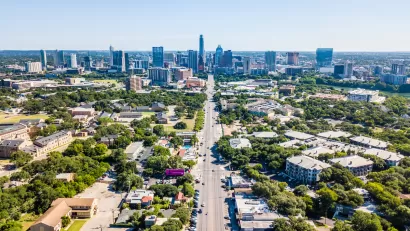 Aerial view of downtown Austin, Texas with state capitol dome at end of long, straight boulevard.