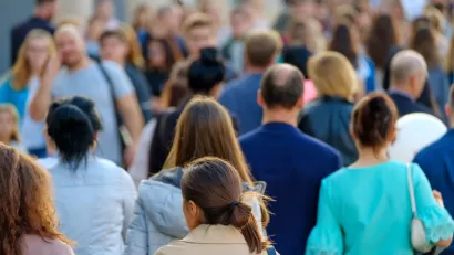 Blurred dense crowd of people with no recognizable faces walking in a busy city.