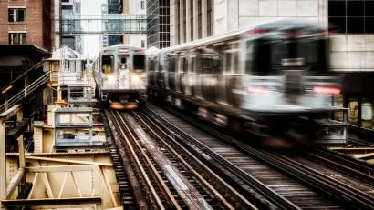 View of two blurred Chicago el trains passing on elevated track between buildings