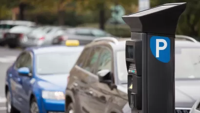 Parking payment machine on street with blurred cars parked in background.