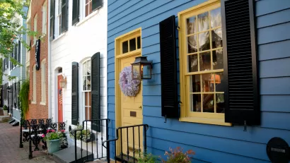 Line of blue, white, and red brick row homes with colorful doors and iron railings.