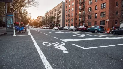 Low view of bike lane on New York City street with bike share station next to curb.