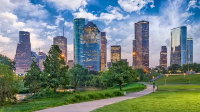 Green lawn and walkway in downtonw Houston park with skyline in background.