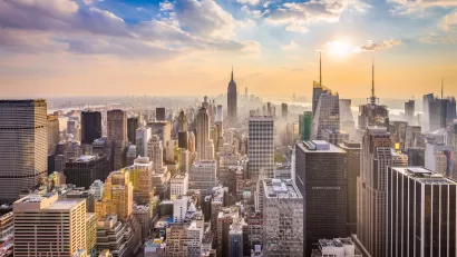 New York City skyline with Empire State Building in center and blue cloudy sky.